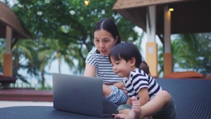 年轻的母亲和她的儿子 (2-3岁) 在周末旅行时在笔记本电脑上工作。
