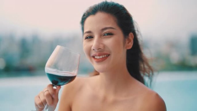 女人在游泳池里享受夏日，喝红酒。