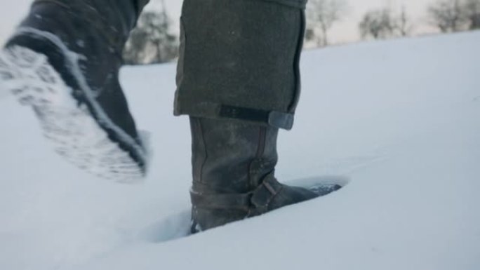 在积雪覆盖的田野中行走的男人靴子的特写镜头