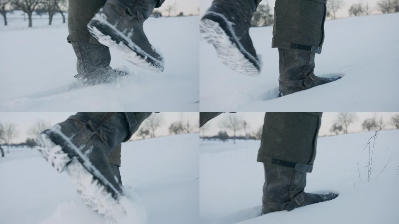 在积雪覆盖的田野中行走的男人靴子的特写镜头