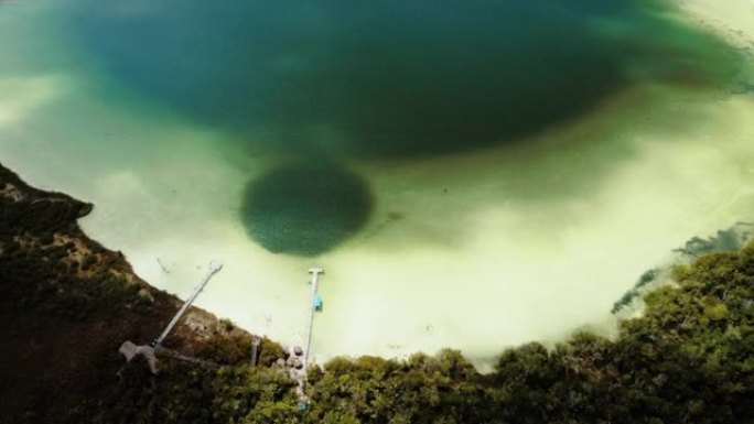 空中无人机拍摄了一个浅湖，周围是两个码头和绿水的植被
