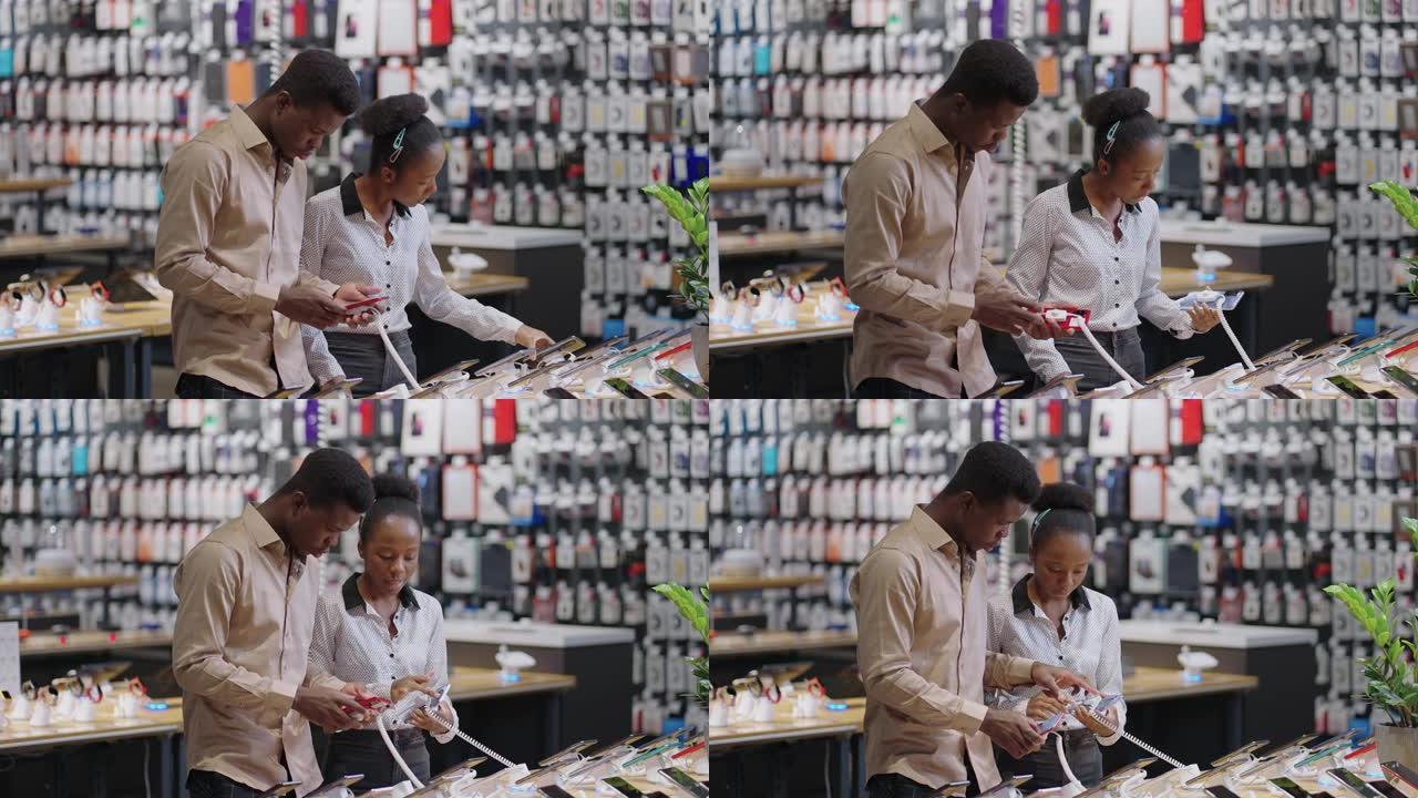 美国黑人已婚夫妇正在数字设备商店中选择智能手机，测试展览样品并讨论模型