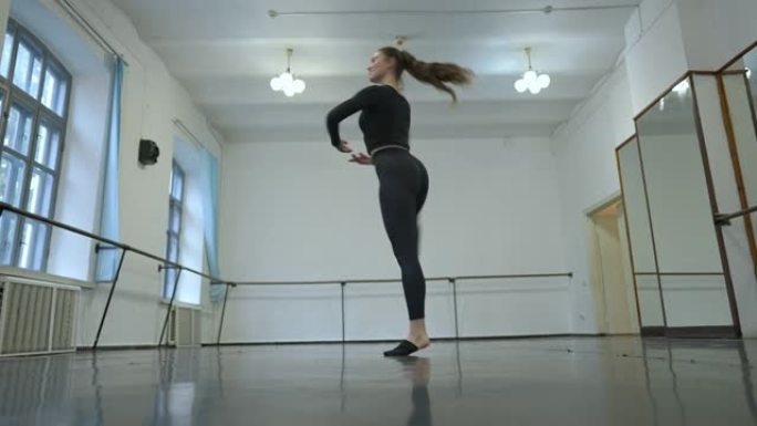 华丽自信苗条的芭蕾舞演员在室内舞蹈工作室旋转。美丽微笑的高加索年轻女子在慢动作中排练表演的肖像。艺术