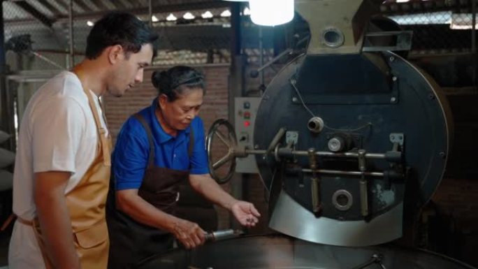 老年妇女咖啡烘焙师正在一个家庭式的小工厂里教一个年轻人咖啡烘焙。