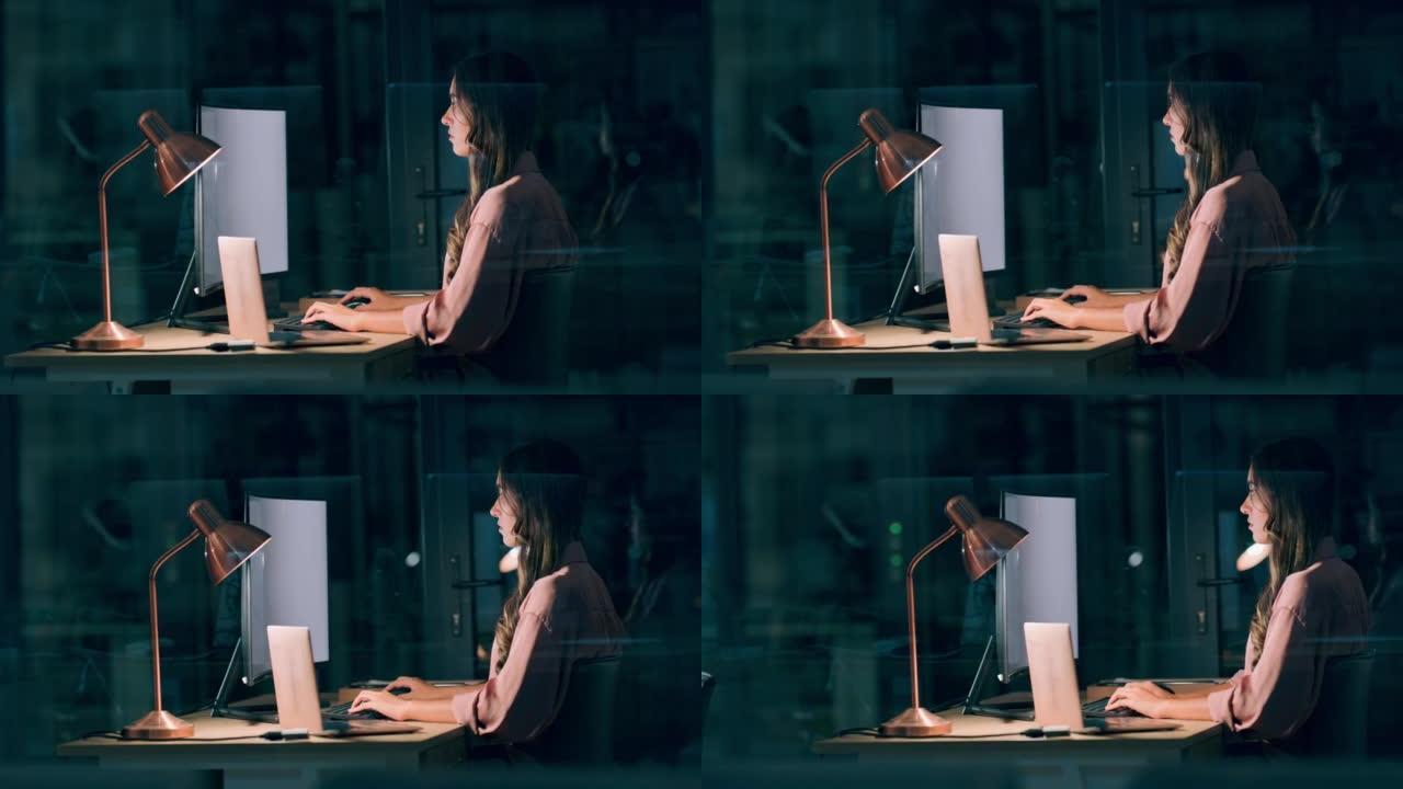 一位女商人深夜坐在办公室。现代科技公司工作时间表灵活的年轻专业人士。女性在数字运动项目上加班以达到最