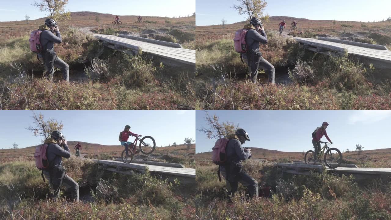 摄影师在晴天在木桥小径上拍摄一对山地自行车夫妇