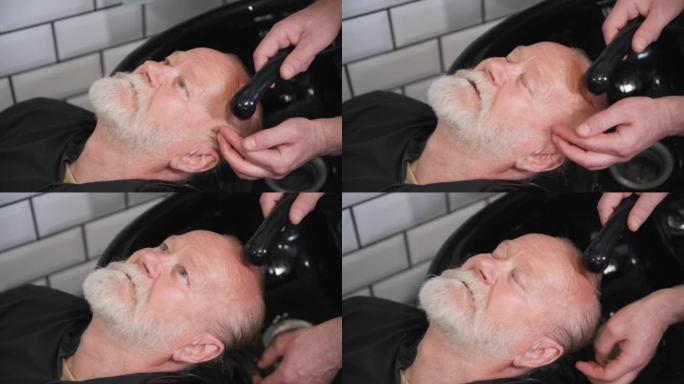 理发店，理发师在理发店洗发前为一位老年顾客洗头