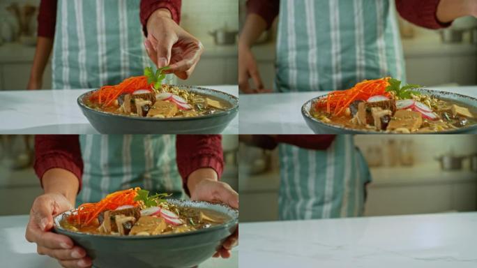 SLO MO雌性手在一碗素食拉面汤上加入欧芹叶