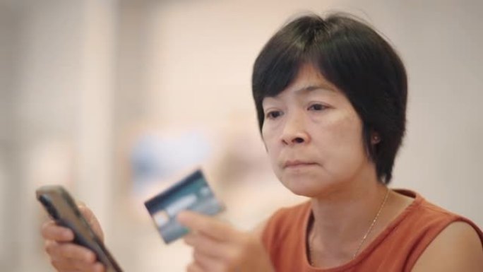 女人手持信用卡，在笔记本电脑上填写信息