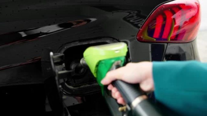 女人的手将手枪插入油箱，使汽车充满汽油或柴油。