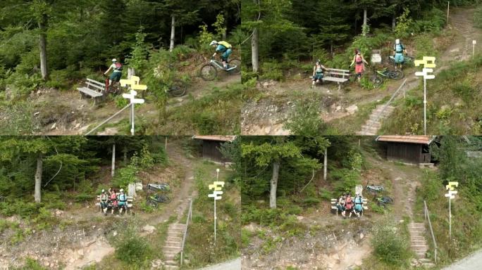 空中无人机拍摄了三名山地自行车手在长凳上休息的镜头