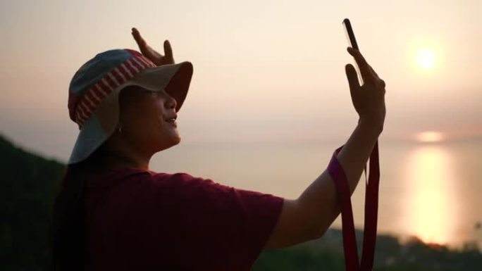 女徒步旅行者在日落时用手机打视频电话