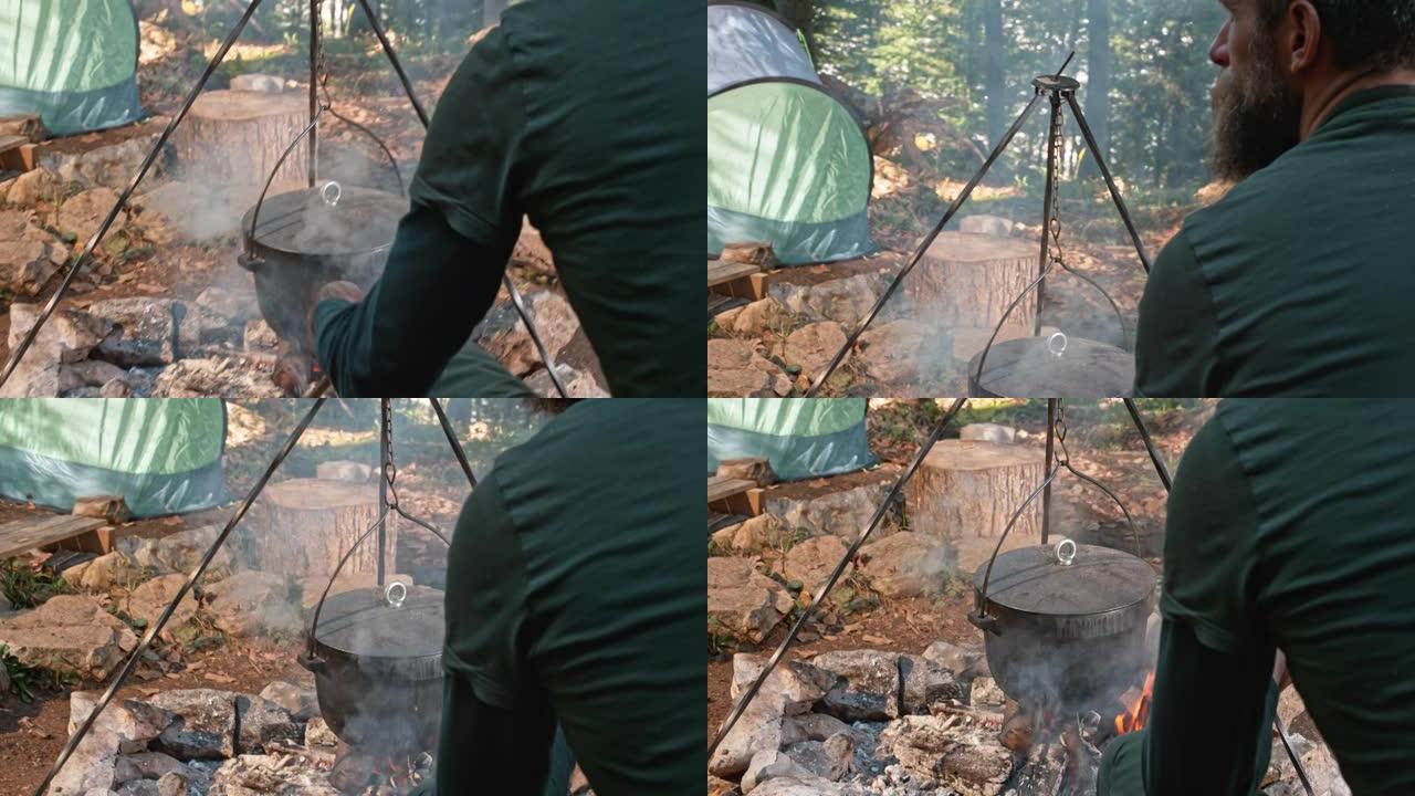 一个人在篝火上用一个铸铁锅煮食物