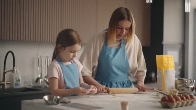母女俩在家庭厨房里煮蛋糕或面包，女人在教孩子做饭