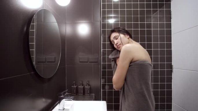 亚洲女性用干净的布擦干自己。洗澡后，清洗身体。在黑色浴室里。