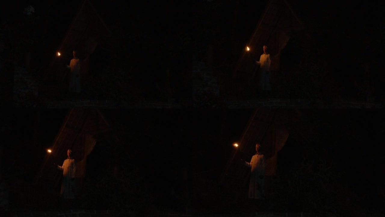 一名穆斯林男子在漆黑的夜晚孤独地站着，手持竹火把