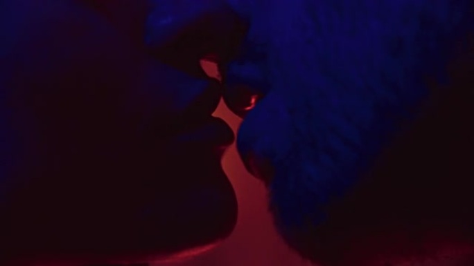 极度亲密的情侣用红色和蓝色的光深情地亲吻