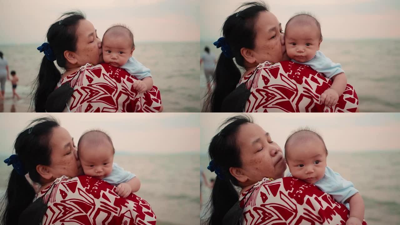 快乐的亚洲祖母抱着她的孙子在海滩上
