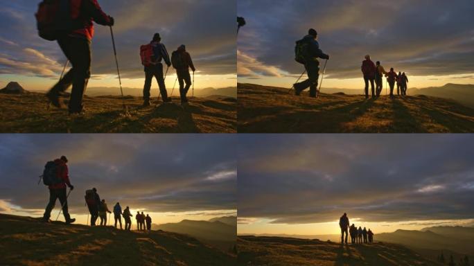 空中SLO MO远足团体在山顶上行走，朝向日落