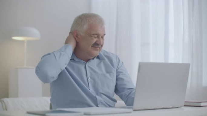 患有颈部骨软骨病的中年男子正在使用笔记本电脑，肌肉过度劳累导致疼痛，按摩自己以放松
