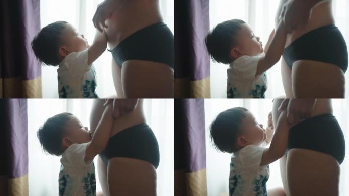 男孩在卧室和怀孕的妈妈肚子玩耍和接吻