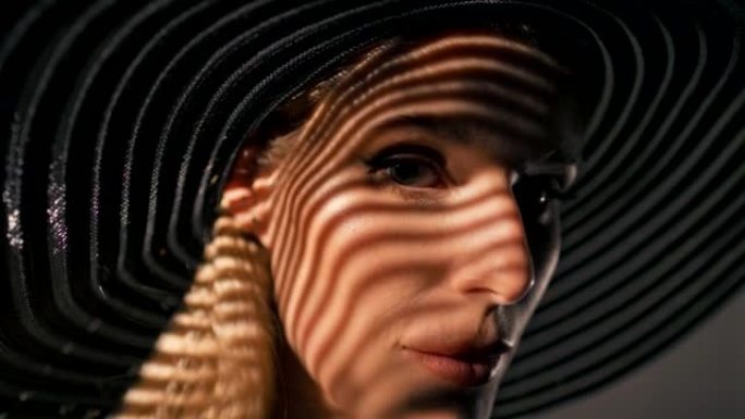 美丽诱人的金发女人用相机调情。戴着大而优雅的帽子摆姿势，遮住她的脸