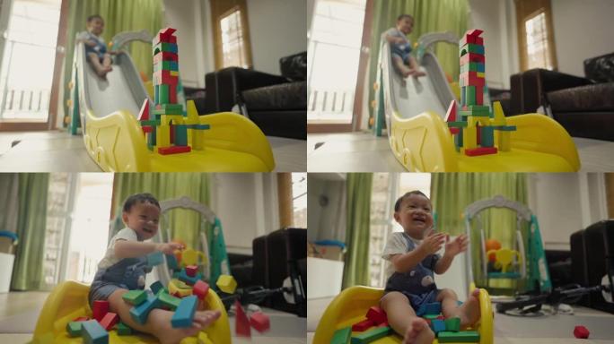慢动作: 男婴放下幻灯片以摧毁玩具块