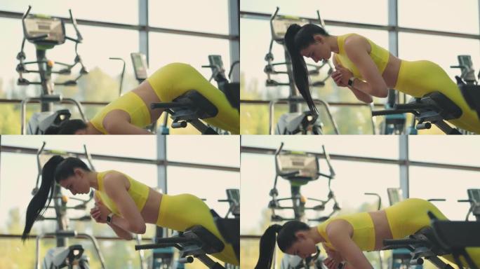 年轻美丽的西班牙裔妇女在健身房进行超延伸。坚定的女人在健身房的长凳上进行背部伸展。强烈的男性能量。健