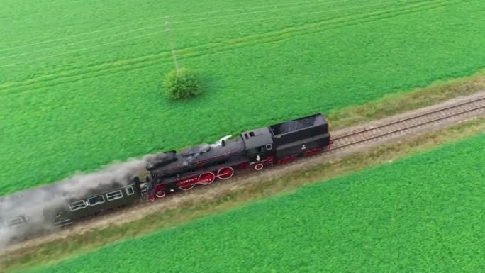 蒸汽火车穿过乡村的田野，鸟瞰图。复古的老式蒸汽机车穿越平原。