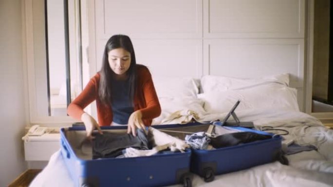 打包旅行，女人在家把衣服打包成行李。