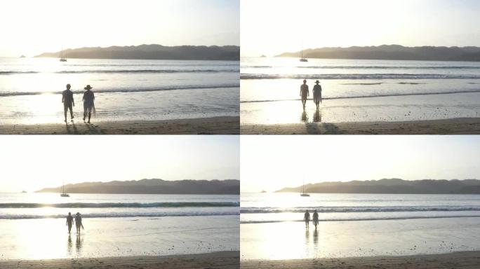 日出时，夫妇在空旷的海滩上散步的鸟瞰图