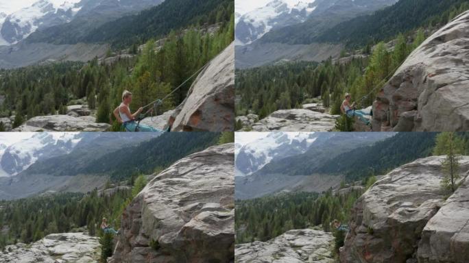 雌性登山者在岩石面上的垂降的无人机视图