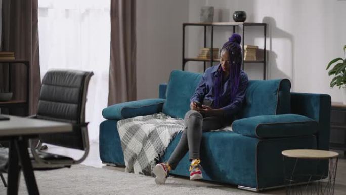 黑人少女正在用智能手机度过周末，上网，观看社交网络