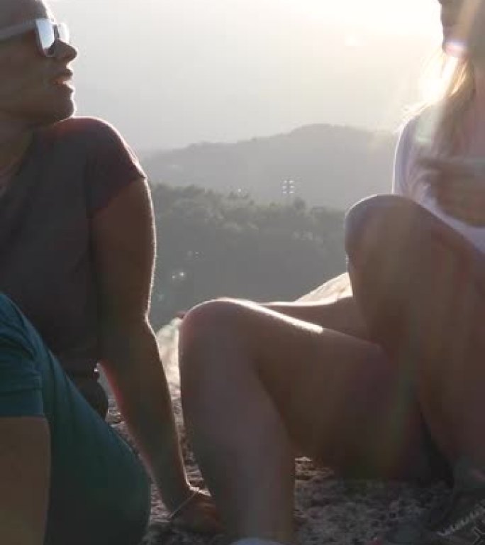 母亲和女儿在日出时在山坡上放松