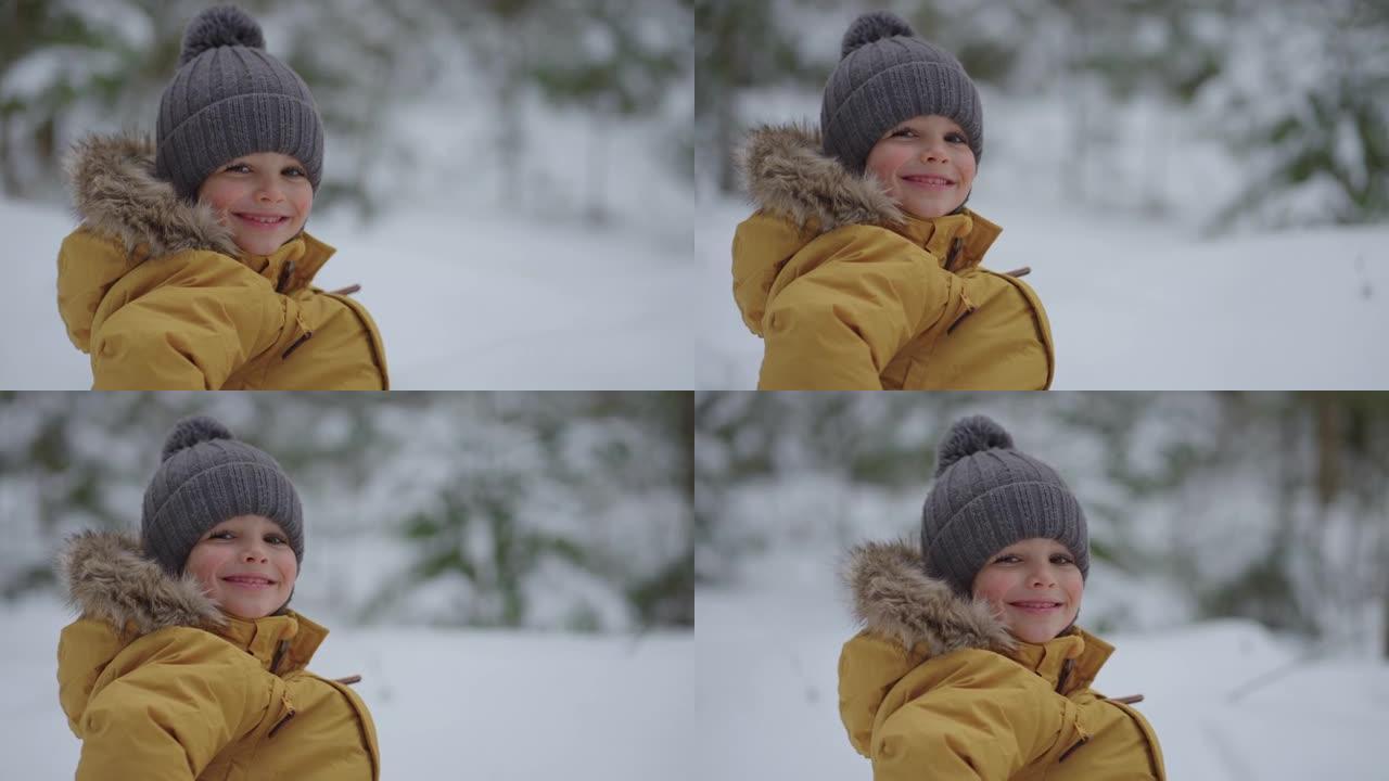 一个微笑可爱的男孩3-4岁的肖像在冬天的森林里的街道上带着快乐的微笑看着镜头在慢动作