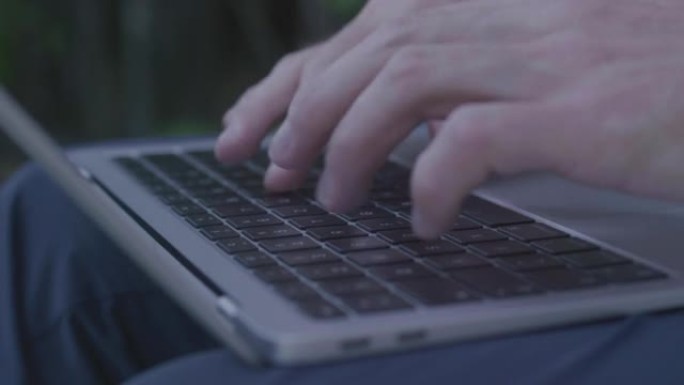 一名男子使用笔记本电脑的细节照片