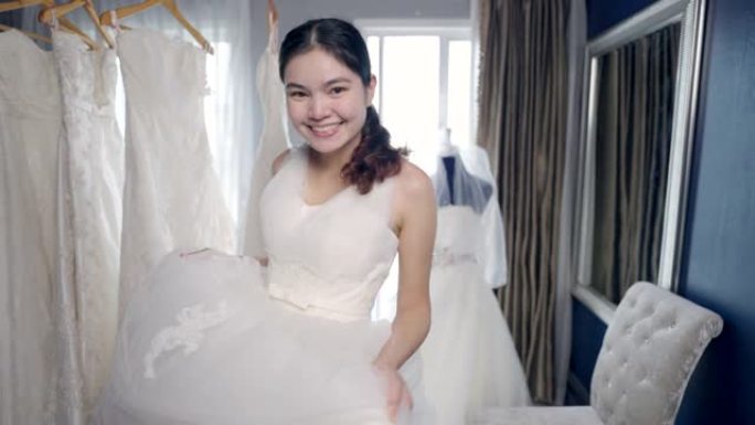 新娘微笑着，喜欢在婚礼工作室试穿新娘礼服。