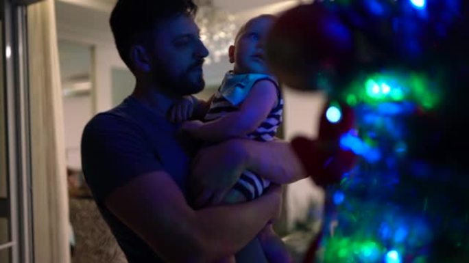 爸爸抱着男婴并展示了被污染的圣诞树