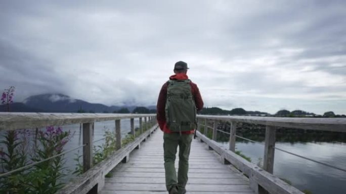 一位年轻的男摄影师在山区海湾附近的木桥上的近距离拍摄