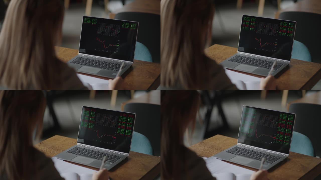 亚洲女商人分析证券交易所图表的图形。一位年轻女性的头部背面，日本，日本，韩国在笔记本电脑的大屏幕上看