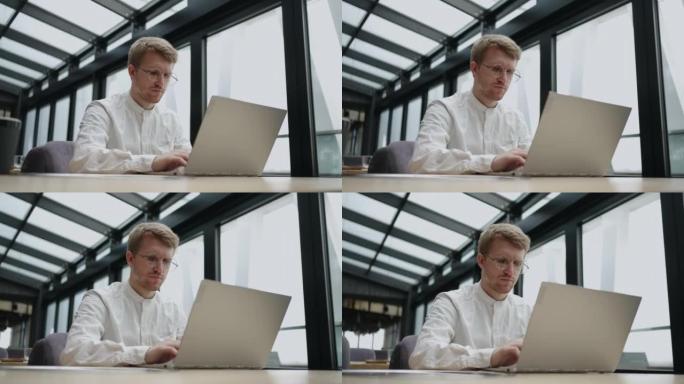 商人在他的现代办公室里使用笔记本电脑，通过互联网发送电子邮件，忙碌而认真的人正在打字