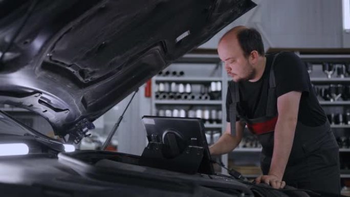 带有平板电脑的汽车引擎盖上的机械师诊断所有系统并搜索故障