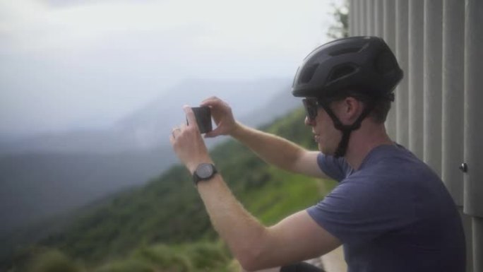 骑自行车的人在山里用电话拍照的棚子附近停下来