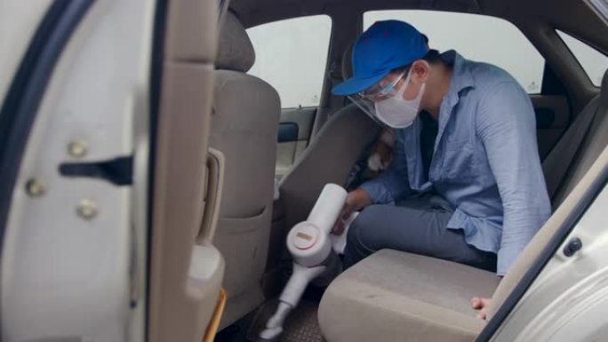 亚洲男子用吸尘器吸尘汽车以预防传染病。