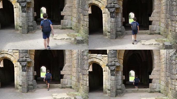 小男孩走过喷泉修道院的中世纪拱门