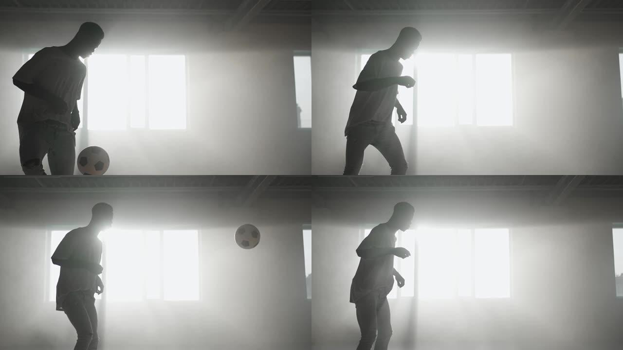 一个黑人在阳光下的地下停车场用球做足球自由泳。慢动作射击在地下停车场玩弄球。