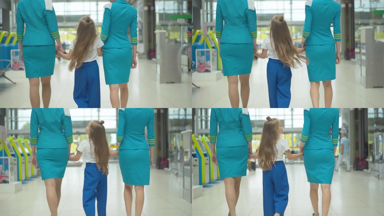 快乐的高加索女孩牵着专业空姐的手，走到机场出口。黑发孩子到达后与空乘人员漫步。陪伴概念。