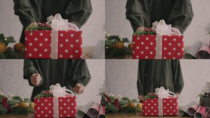 相机跟随礼物。一个女人用手将一个装有装饰品的圣诞盒子推入相机。环保材料亲手制作的绿色圣诞礼物