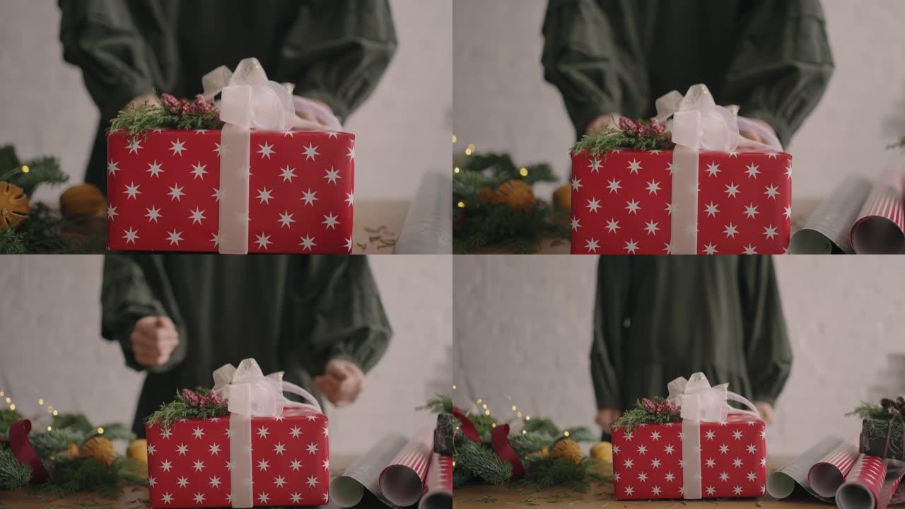 相机跟随礼物。一个女人用手将一个装有装饰品的圣诞盒子推入相机。环保材料亲手制作的绿色圣诞礼物