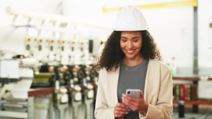 女厂长的画像拿着电话查看里面的在线发货app自信的微笑仓库主管戴着安全帽，在带有机械和硬件的储藏室中